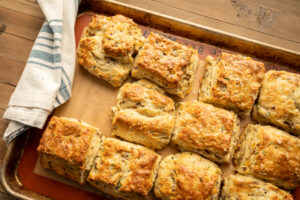A tray of biscuits from the oven. The biscuits are square shaped and filled with sausage, cheddar and parsley.