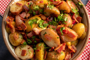 Warm bacon potato salad with crispy Hempler's bacon, baby potatoes, fresh parsley, and a tangy dressing, perfect for summer cookouts and BBQs.