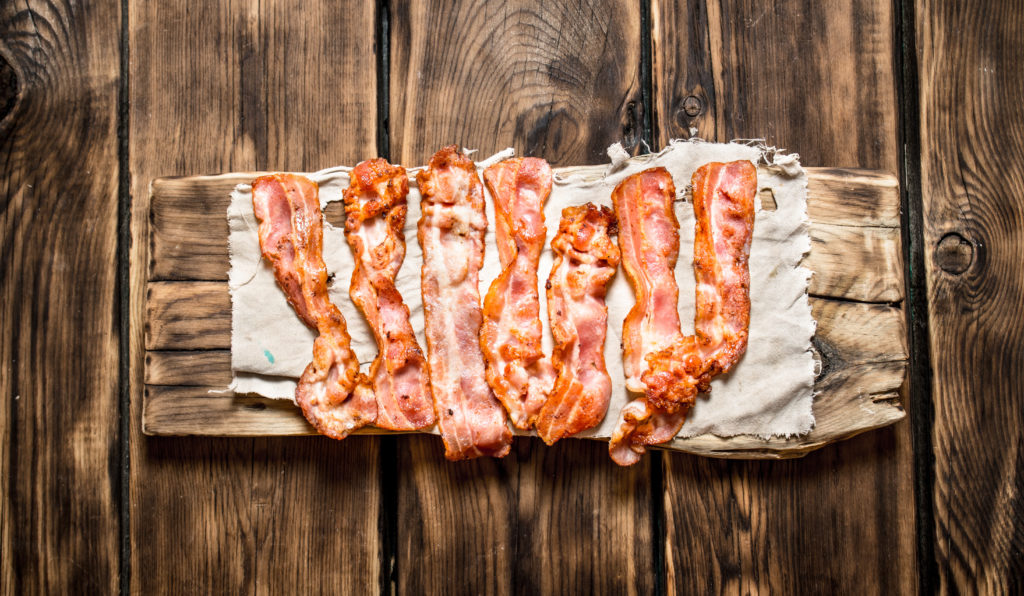 Fried bacon on the fabric. On a wooden table.
