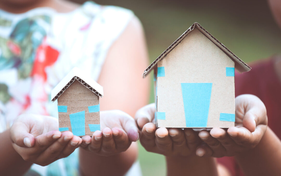 Child and parent holding paper house in hands as real estate and family home concept